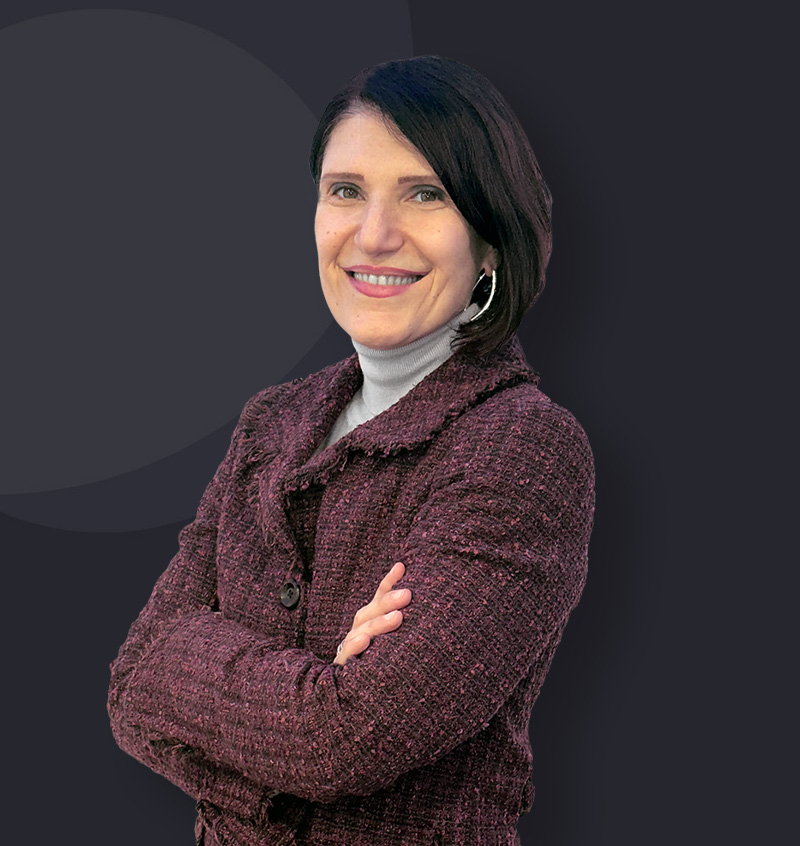 Paola Gabrici di Formazione per Dirigenti in una foto a mezzo busto con un completo elegante scuro e mani conserte.